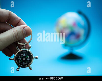 Petite boussole en forme de volant de la marine et des flous d'arrière-plan sur le globe. cruise travel concept. selective focus on foreground Banque D'Images