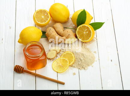 Racine de gingembre, citron et miel sur fond de bois blanc Banque D'Images