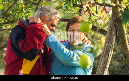 Portrait de femme mature de rire avec son mari alors qu'il la serre et elle looking at camera Banque D'Images