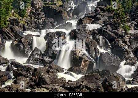 Belle cascade avec de l'eau lisse tomber entre les roches et les pierres noires dans les montagnes, tourné sur une longue exposition Banque D'Images