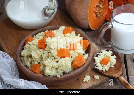 Porridge de millet avec citrouille dans un bol en bois et d'une cruche et un verre de lait Banque D'Images