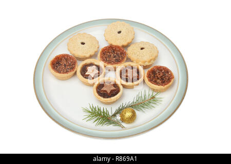 Petits pâtés de fête sur une assiette décorée avec des aiguilles de pin et une boule d'or blanc isolé contre Banque D'Images