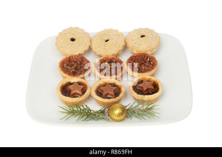 Petits pâtés de fête sur une assiette décorée avec des aiguilles de pin et une boule d'or blanc isolé contre Banque D'Images