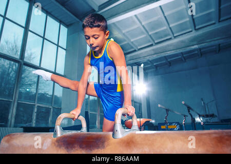 Le sportif l'exécution difficile exercice de gymnastique à la salle de sport. Le sport, exercice, gymnaste, la santé, la formation, le concept de l'athlète. Bon petit garçon caucasien Banque D'Images