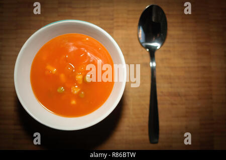 Still Life de soupe de tomate dans un bol de céramique blanche ronde avec sur une planche de bois et d'une cuillère. Banque D'Images