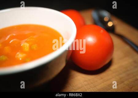 Still Life de soupe de tomate dans un bol de céramique blanche ronde avec sur une planche de bois et d'une cuillère. Banque D'Images