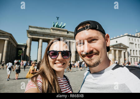 Belle jeune couple contre selfies l'arrière-plan de la porte de Brandebourg à Berlin en Allemagne. Banque D'Images