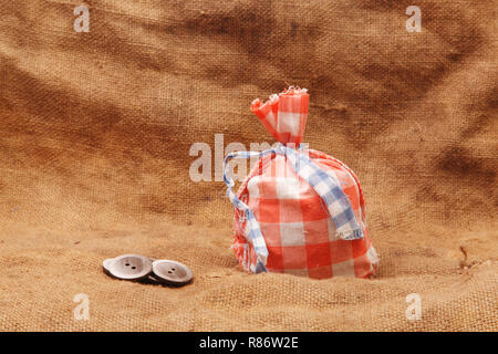 Sac rouge et boutons sur un fond de toile de jute Banque D'Images