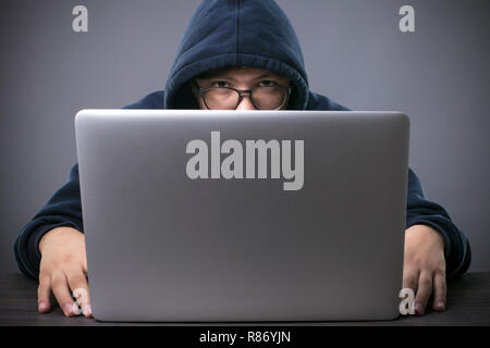 Hacker dans le capot, devant un ordinateur portable a l'air dans l'appareil photo Banque D'Images