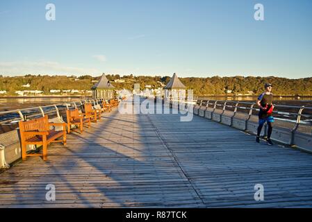 Un jeune homme jogger court le long de la jetée de Bangor à l'aube, Bangor, Gwynedd, au nord du Pays de Galles, Royaume-Uni Banque D'Images