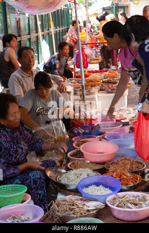 Photo verticale des étals du marché en plein air avec des gens l'achat et la vente de fruits de mer séchés. Banque D'Images