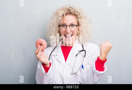 Jeune blonde dietist médecin femme de plus grunge grey wall eating crier fier et célébrer la victoire et le succès très excités, ils applaudissent emoti Banque D'Images