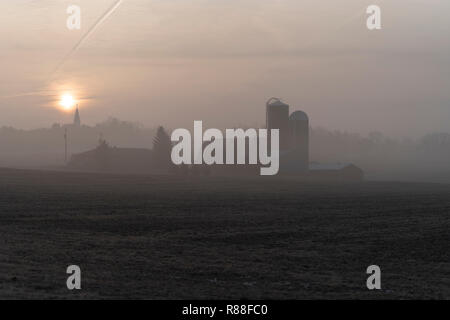 Lever de soleil à la ferme du Wisconsin pendant une matinée froide et brumeuse. Banque D'Images