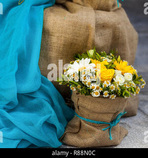 Marguerites jaunes et roses jaunes bouquet présenté et décoré dans un sac de jute sac au sol .Image. Banque D'Images