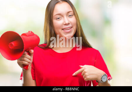 Young caucasian woman yelling through megaphone sur fond isolé avec surprise face à face à lui-même Banque D'Images