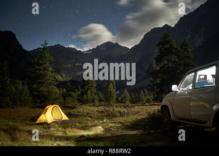 Camping avec une voiture, tente jaune dans la nuit avec un clair de lune, sur la zone de montagne Banque D'Images