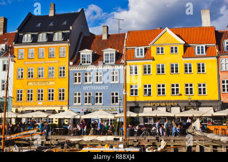 Au bord du canal en plein air des tables et des chaises et des maisons peintes de couleurs vives, Nyhavn, Copenhague, Danemark, Scandinavie Banque D'Images