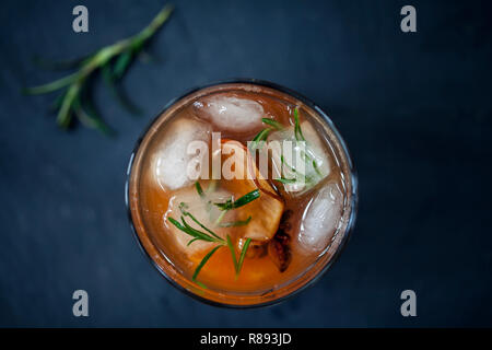 Verre de whisky, à l'ancienne avec des cubes de glace romarin sec et tranche de poire Banque D'Images