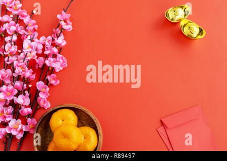 Mise à plat fond Nouvel An chinois - Fleur de cerisier, mandarine, orange, rouge et enveloppent les lingots d'or sur fond rouge. Banque D'Images