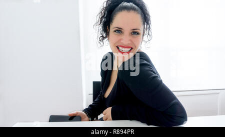 Portrait d'une belle femme normale en utilisant son téléphone portable et souriant aux cheveux noirs, la peau blanche et rouge lèvres. Copy space Banque D'Images