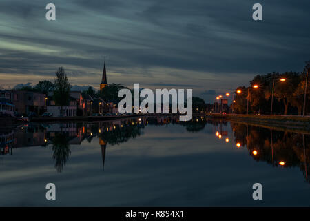 Ville néerlandaise avec tour de l'église près de Gouda avec reflets dans l'eau à l'heure bleue. Belle scène avec une perspective nuages de rêve. Banque D'Images