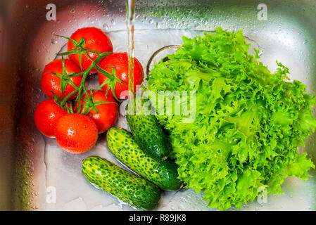 Des légumes frais des concombres, des tomates et de la salade dans l'évier dans la cuisine Banque D'Images