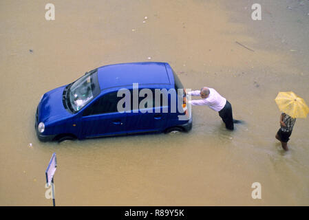 En raison des inondations à Heavy Rain, poussant l'homme voiture sur la route inondée, Bombay Mumbai, Maharashtra, Inde Banque D'Images