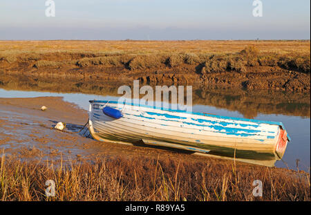 Un petit bateau laissé attaché dans un ruisseau dans les marais salés de la côte nord du comté de Norfolk à Blakeney, Norfolk, Angleterre, Royaume-Uni, Europe. Banque D'Images