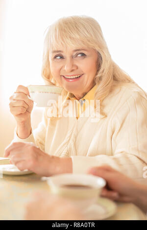 Belle femme Senior bénéficie du plateau au café. Femme souriante un goût thé aromatique Banque D'Images