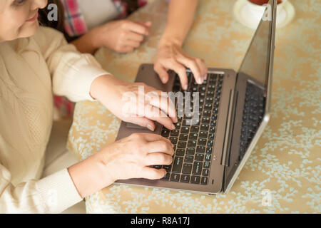 Plan rapproché sur Senior Woman's Hands Typing sur l'ordinateur portable du clavier. L'apprentissage de travailler avec un ordinateur Banque D'Images