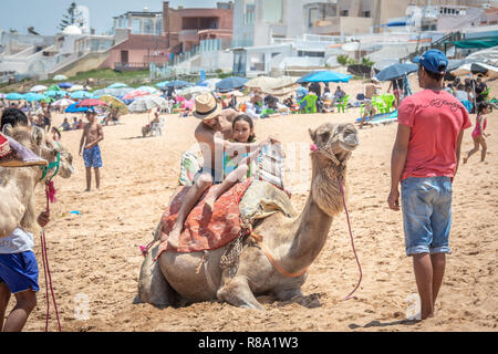 Un père et sa fille se préparent à monter un chameau sur les plages de Bouznika, Casablanca-Settat, Benslimane, Maroc Banque D'Images