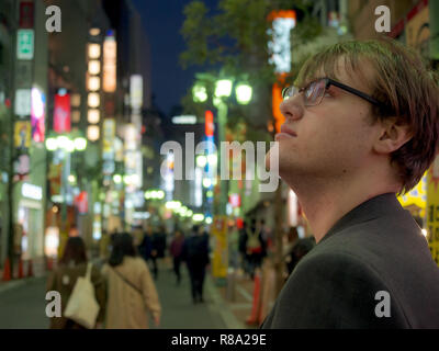 Un jeune homme à la découverte de la lumières des néons d'une grande ville asiatique Banque D'Images