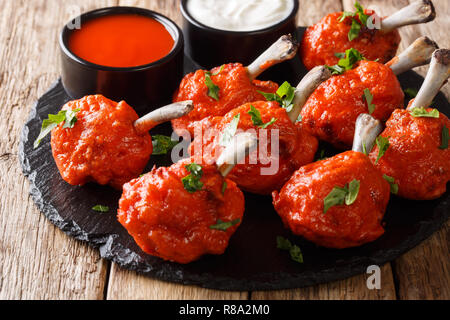 Menu buffet de sucettes rouges frits des ailes de poulet servi avec des sauces close-up sur une liste de sélection sur une table de bois horizontal. Banque D'Images