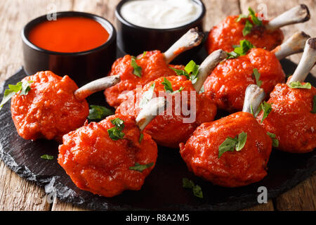 Sucettes apéritif rouge frit servi avec des sauces, les ailes de poulet sur une liste de sélection sur une table de bois horizontal. Banque D'Images