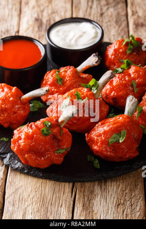 Les lollipops en friture, les ailes de poulet en sauce rouge gros plan sur une liste de sélection sur une table en bois. La verticale Banque D'Images