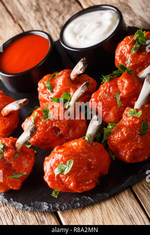 De délicieuses Sucettes friture des ailes de poulet en sauce gros plan sur une liste de sélection sur une table en bois vertical. Banque D'Images