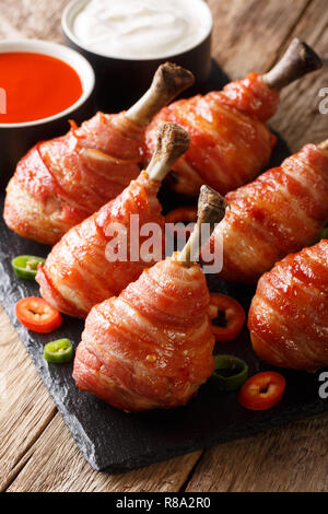 Cuisses de poulet au bacon sucettes avec des sauces sur la table. vertical Banque D'Images