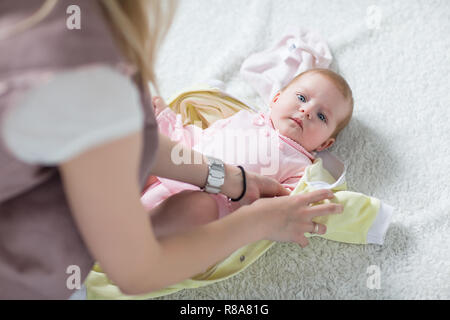 Maman met des vêtements sur le bébé. Femme met son bébé. Banque D'Images