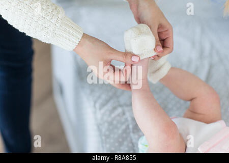 Maman met des vêtements sur le bébé. Femme met son bébé. Banque D'Images