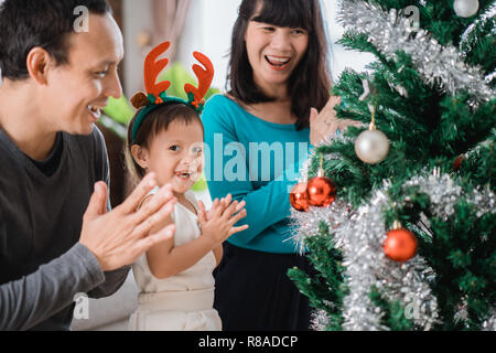 Portrait de fille de bonheur avec son père et sa mère de préparer un arbre de Noël à la maison Banque D'Images