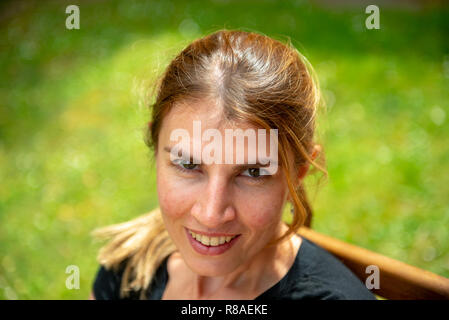 Tête portrait de la jeune femme en souriant à l'appareil photo prise de la ci-dessus. Banque D'Images