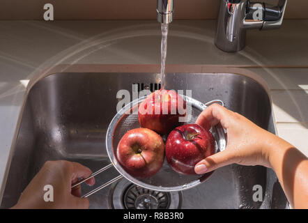Lave-mains femme pomme rouge dans l'eau de la crépine Banque D'Images