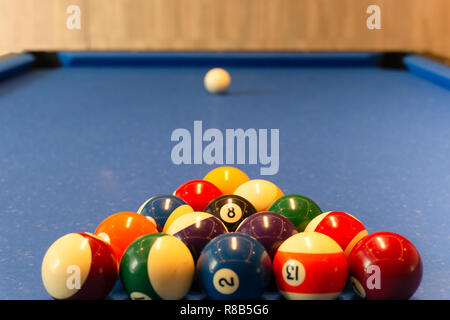 Boules de billard multi couleur se trouvent sur le tissu bleu table dans le triangle Banque D'Images