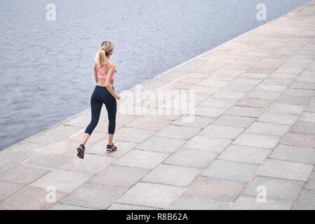 Sérieux au sujet de rester en forme. Vue de dessus de jeune femme en vêtements de sport jogging lors de l'exercice en plein air Banque D'Images