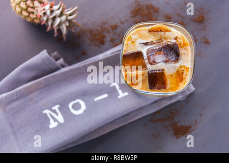 Un verre de lait avec des cubes de café glacé sur fond sombre. lettres numéro 1 et ananas Banque D'Images