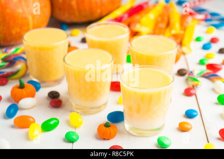 Citrouille Halloween party avec boisson et bonbons sur table en bois blanc Banque D'Images