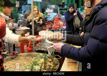 Un chef italien autre qu'un client un carton alimentaire avec de l'épeautre risotto aux champignons sauvages, chaud la cuisson à Borough Market stall London England UK KATHY DEWITT Banque D'Images