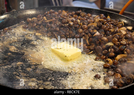 Un bloc de beurre grésiller sur une cuisinière poêle avec les champignons sauvages en préparation pour faire un risotto au Borough Market stall à Londres UK KATHY DEWITT Banque D'Images