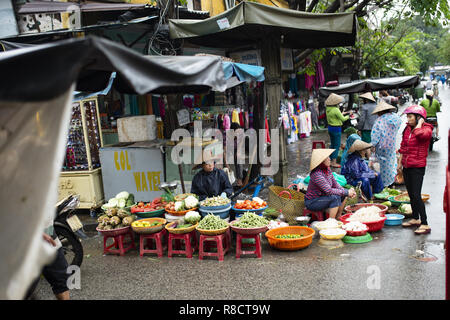 Certaines personnes avec le chapeau conique vietnamien typique vendent des légumes frais dans un marché de rue, Hoi An. Banque D'Images