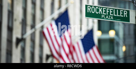 Vue rapprochée de la rue verte représentant signe 'Rockefeller Plaza' dans Midtown Manhattan, New York. Des drapeaux américains flou en arrière-plan. Banque D'Images